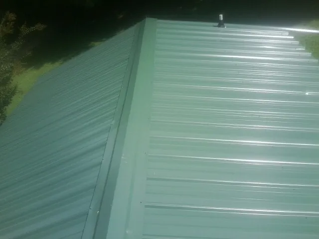 New green metal panels meeting at the ridge of a roof — Flat Roof Repair work by our crew in Township Of Washington