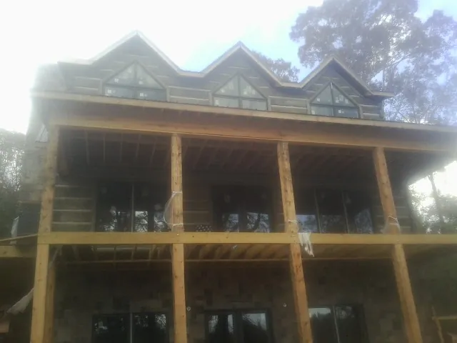 Dormers and porch framing on a large log home under construction — Roof Coating work by our crew in Township Of Washington
