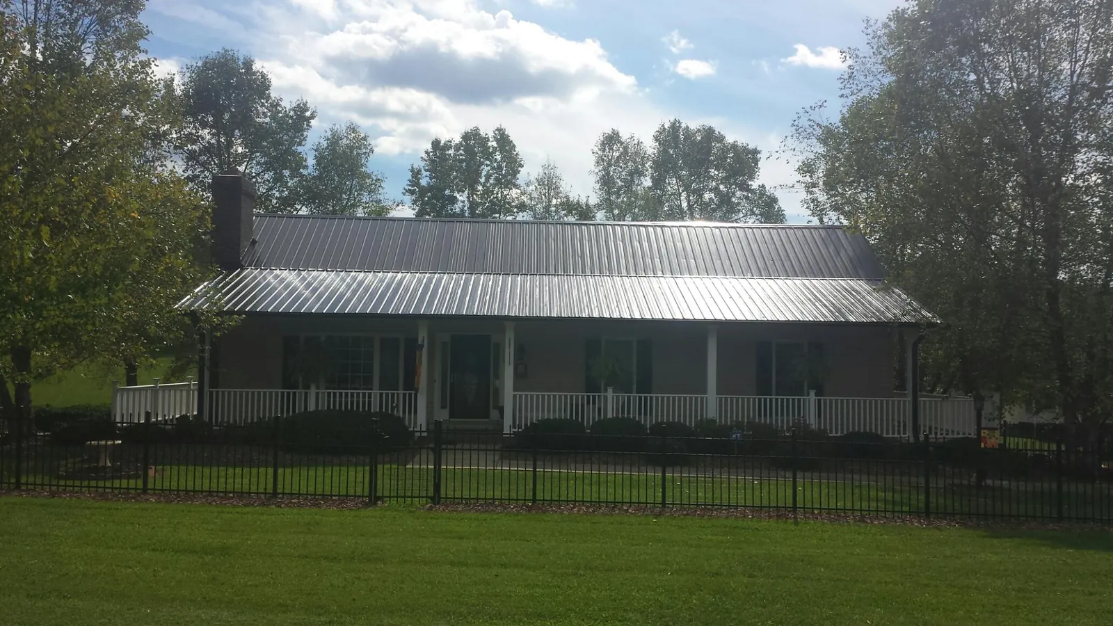 Gray metal roof on a brick ranch with a full width front porch — Gutter Guard Installation work by our crew in Township Of Washington