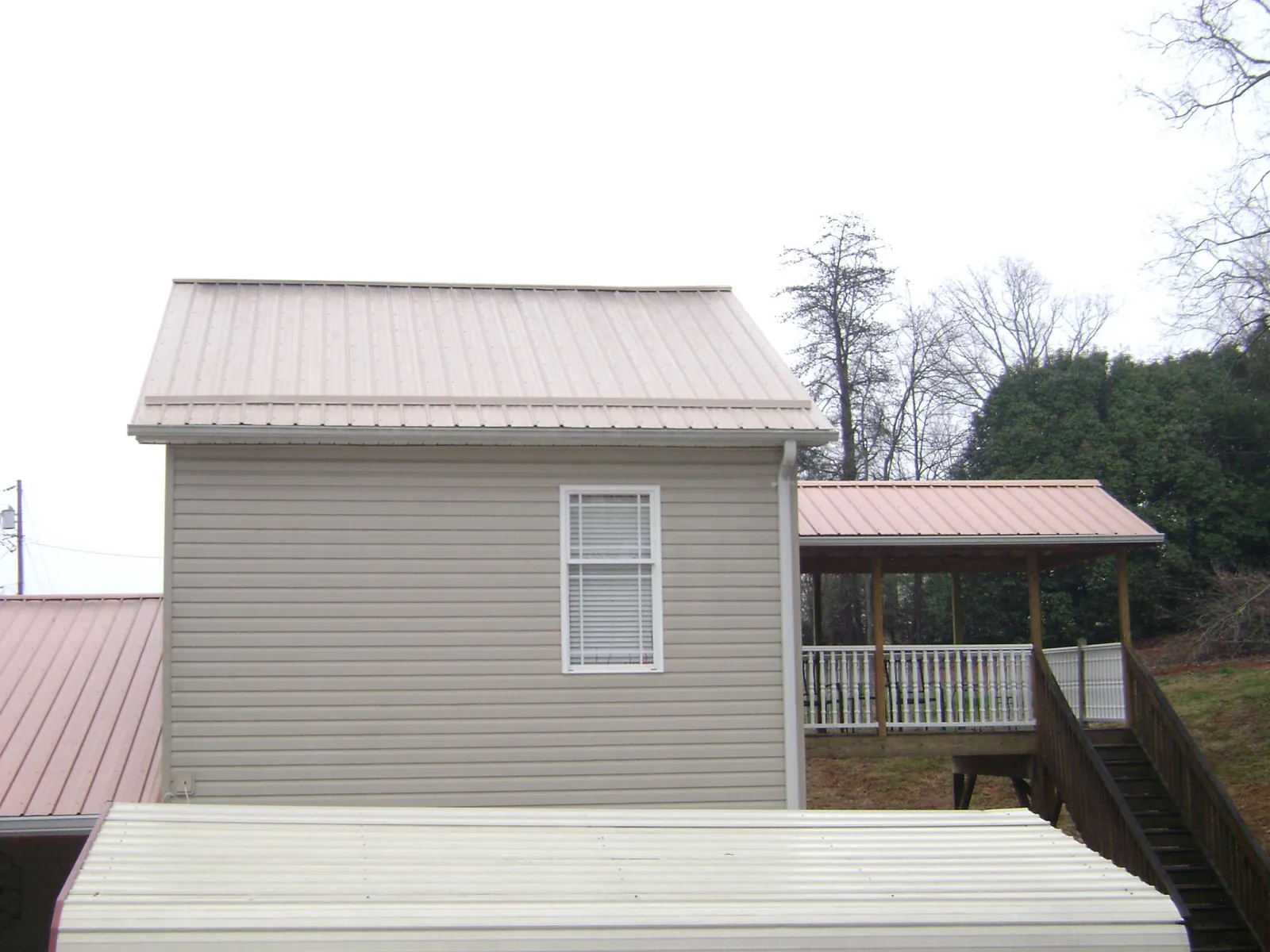 Tan metal roofs on a two story addition and attached porch, from a Roof Replacement job in Township Of Washington