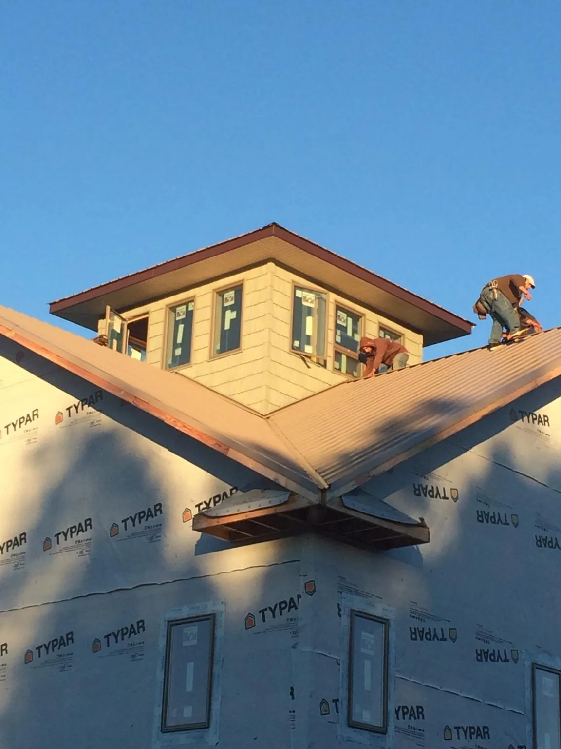 Roofers working around a rooftop cupola on a new metal roof at sunset — Roof Waterproofing in Township Of Washington by Roofing Brothers